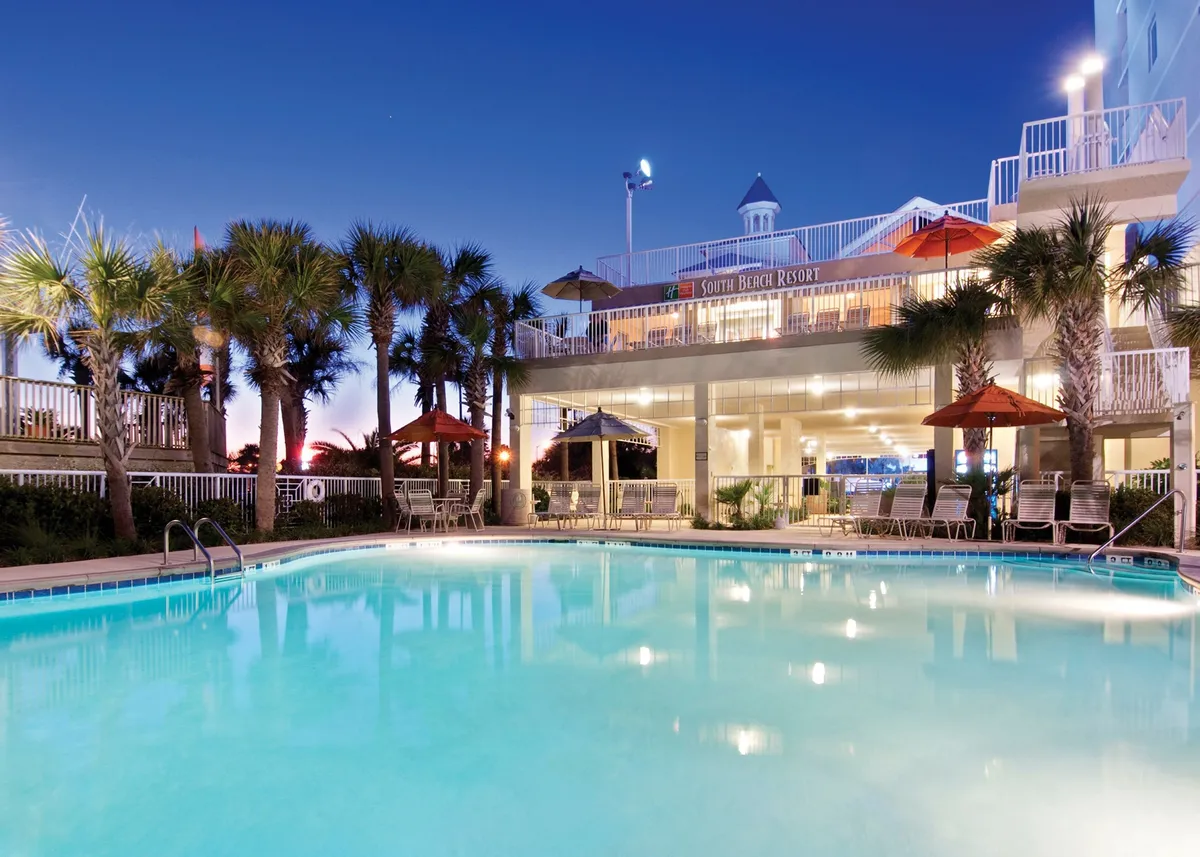 An inviting exterior view of the resort’s swimming pool area surrounded by tropical palm trees, outdoor seating, and umbrellas. The mood is serene, with hints of relaxation and celebration, and sunset views provide a tranquil atmosphere.
