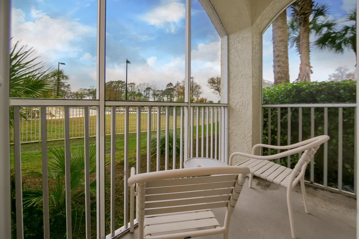 The image showcases a tranquil outdoor seating area enclosed by screens, surrounded by lush greenery. The space feels private and serene, perfect for unwinding and enjoying gentle sunrise views or cool evening breezes. The inviting setup suggests a spot ideal for quiet relaxation, reading, or intimate conversations.